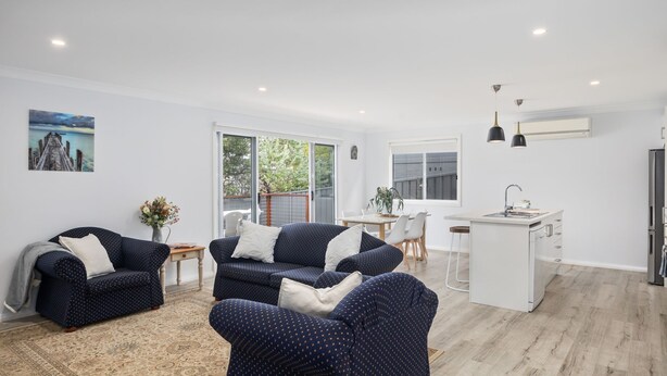 A modern living room with two sofas, a dining area, and a kitchen. - Tallwood By The Sea in Mollymook (Mollymook)