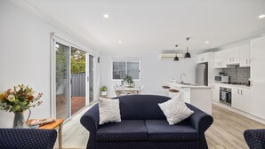 A modern kitchen with white cabinets, a built-in oven, and a microwave. - Tallwood By The Sea in Mollymook (Mollymook)