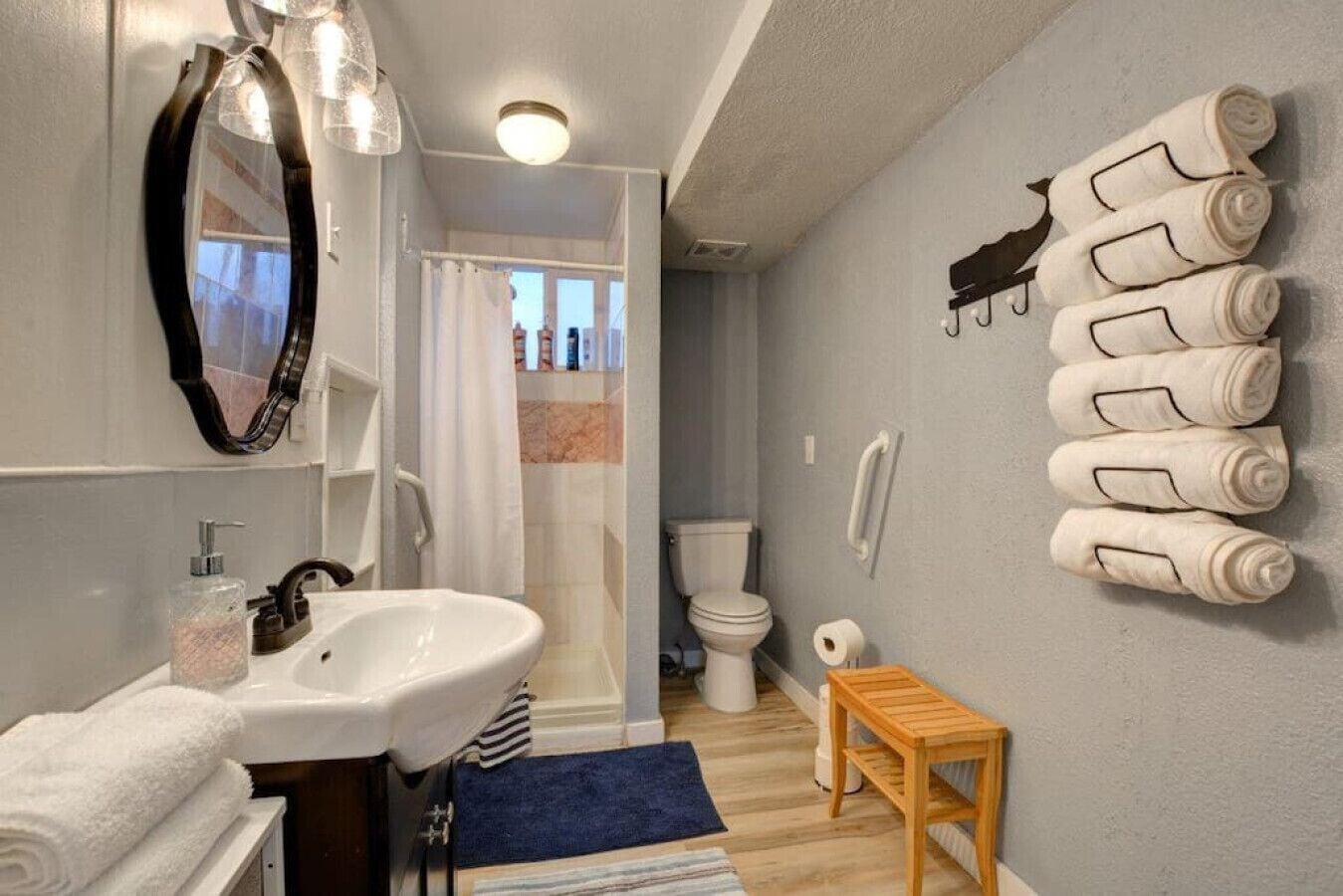 Et badeværelse med vask, spejl, håndklædestang, bruser og toilet.