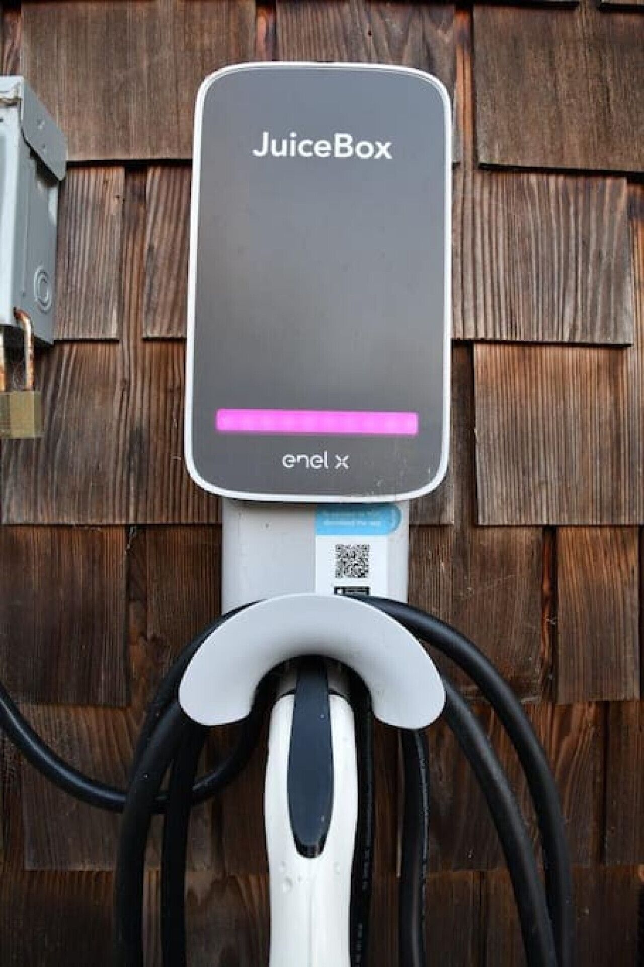 En JuiceBox opladningsstation med et Enel X logo, forbundet til et kabel.