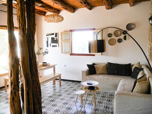 Ein Wohnzimmer mit Holzboden, einer Couch, einem Couchtisch und einem Esstisch mit Stühlen.
