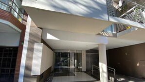 A modern building entrance with a glass door, a metal staircase, and a tiled floor.