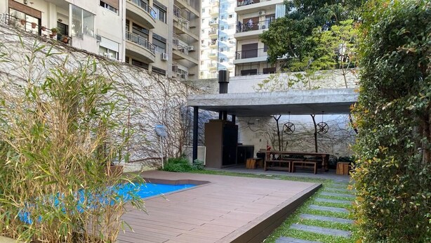 A rooftop garden with a swimming pool, outdoor seating, and a view of surrounding buildings.