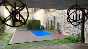 A courtyard with a blue pool, wooden deck, and hanging rope decorations.