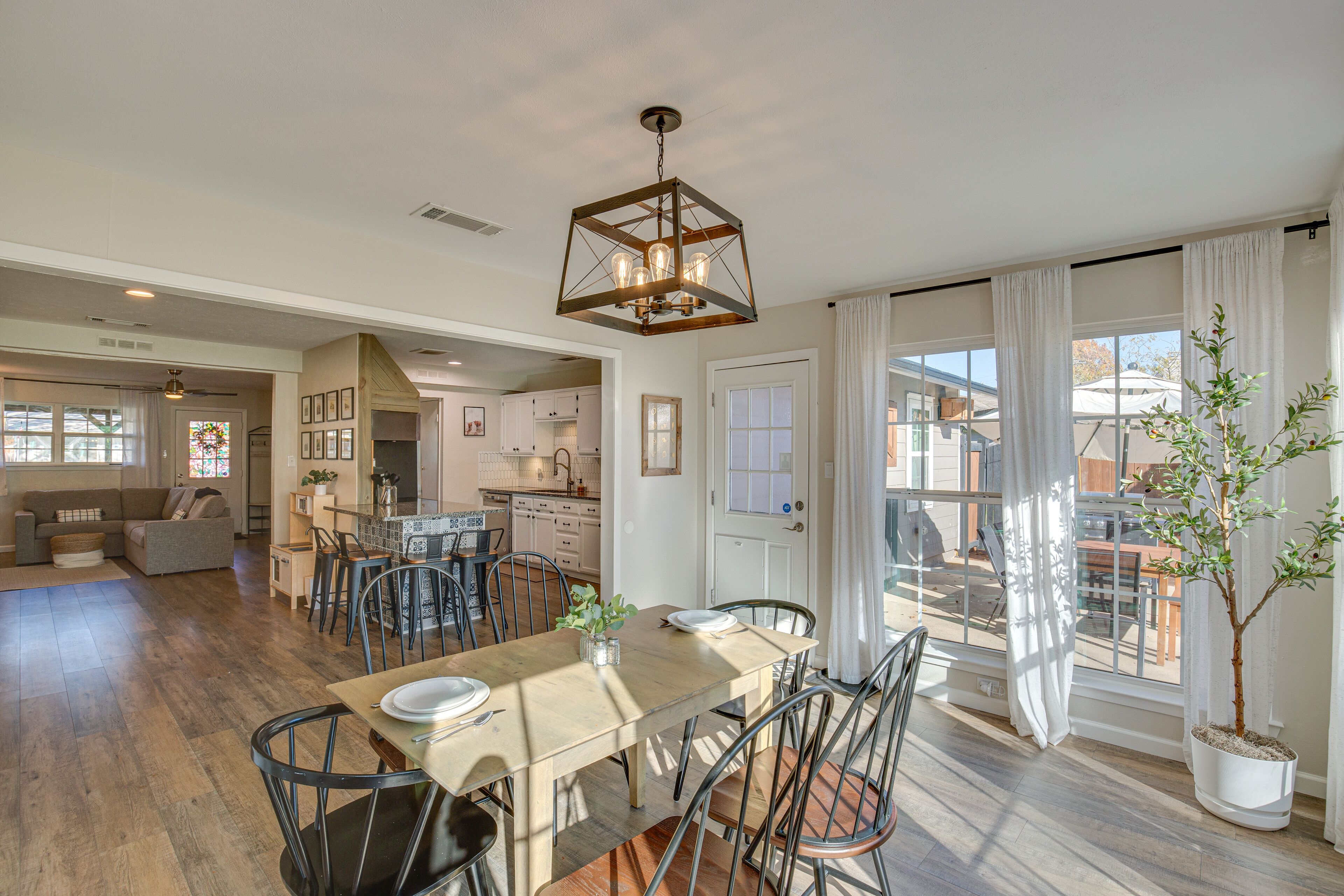 A spacious dining area with a wooden table, metal chairs, and a hanging light fixture.