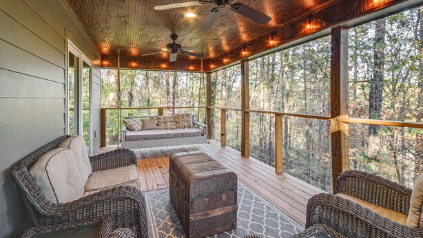Un espace extérieur aménagé, abrité et doté de mobilier en osier, d’un ventilateur de plafond et d’une vue sur la forêt.