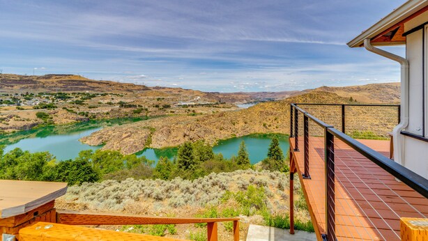 A balcony with a view of a river and hills.