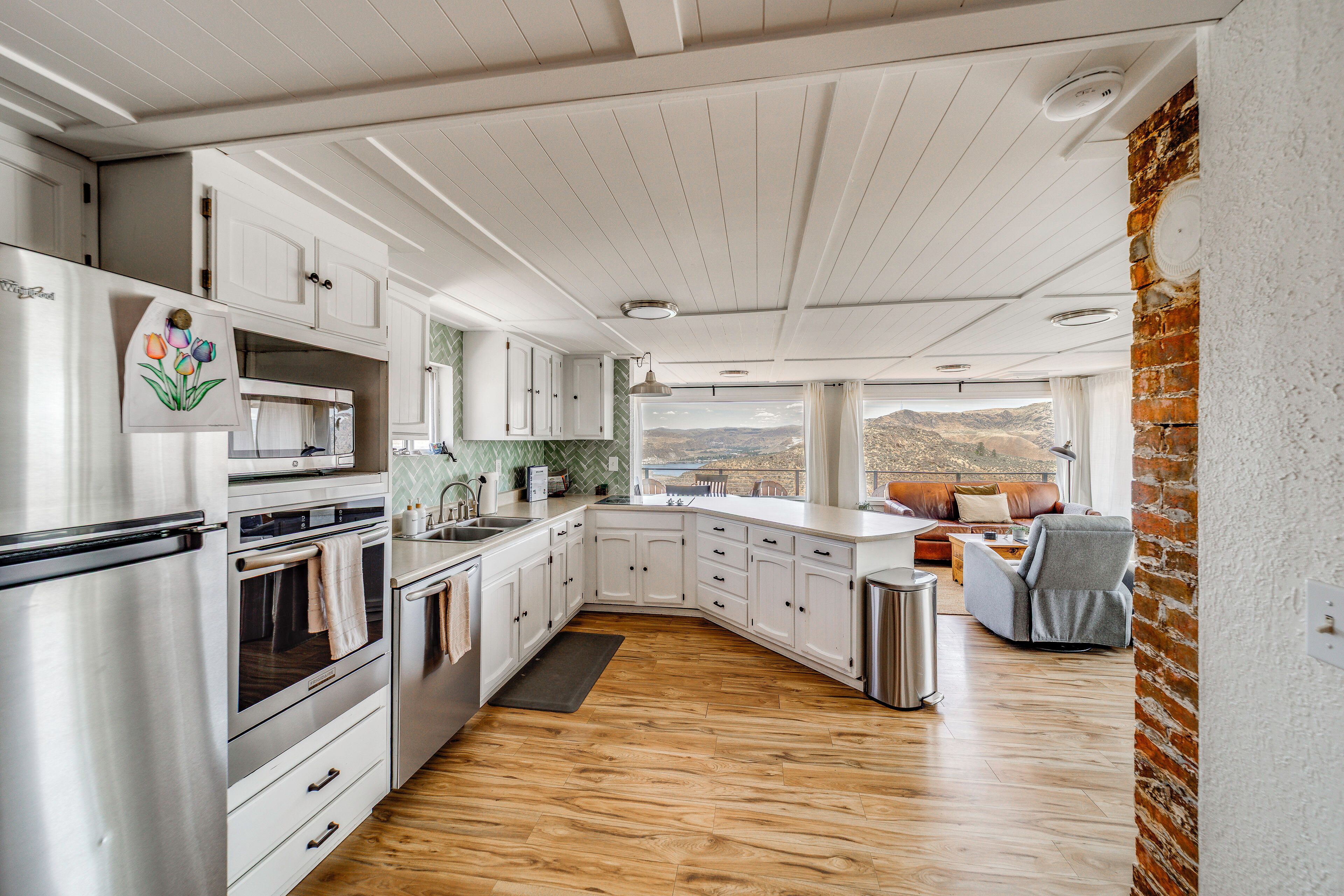 Une cuisine moderne avec des meubles blancs, des appareils électroménagers en acier inoxydable et un plancher en bois.