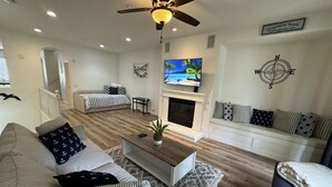 A living room with a sofa, coffee table, and a fireplace. - Coastal Condo - Gated, Pool, Spa, Walk To The Beach (Huntington Beach)