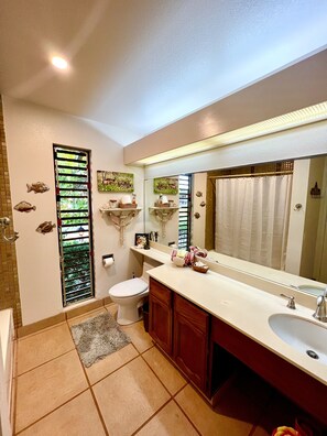 Une salle de bain avec des toilettes, un lavabo et un miroir. Il y a des poissons décoratifs sur le mur et un rideau de douche.