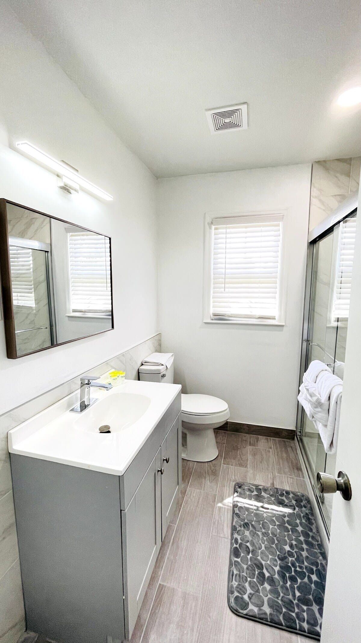 A modern bathroom with a white sink, toilet, and shower.