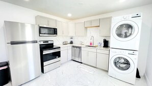 Una cocina moderna con electrodomésticos de acero inoxidable, armarios blancos y un horno empotrado.