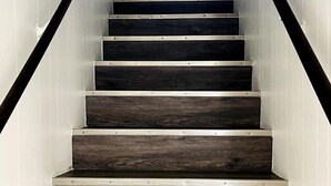 Una escalera con escalones de madera oscura y barandillas negras.