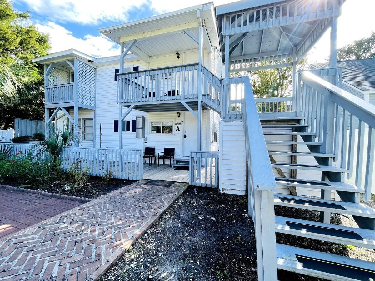 A two-story house with a covered porch and a brick pathway leading to the entrance.