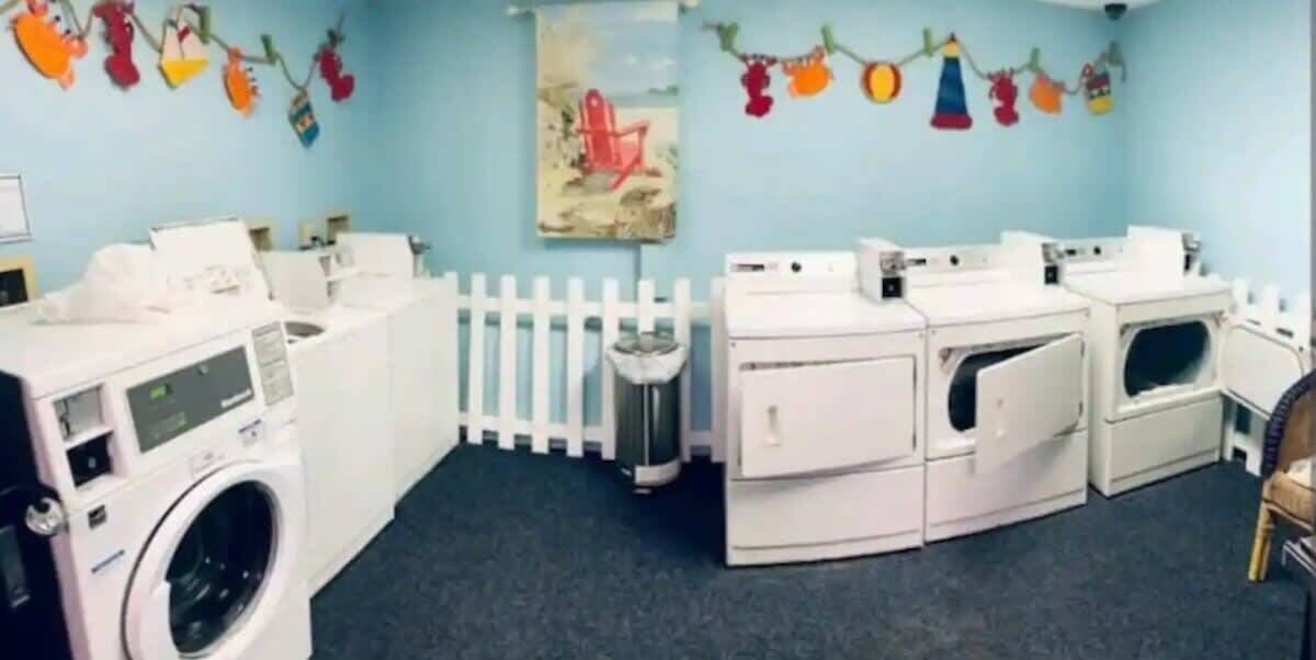 A laundry facility with multiple washing machines, a white fence, and colorful decorations on the walls.