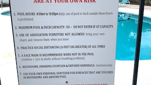 A sign detailing COVID-19 pool rules at Villas on the Green, including pool hours, capacity limits, and safety guidelines.