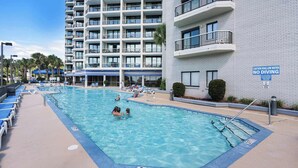 A swimming pool with a 3 ft depth warning, a no diving sign, and a building with balconies in the background. - Carolina Winds #5 beautiful Ocean view condo, pool (Myrtle Beach)