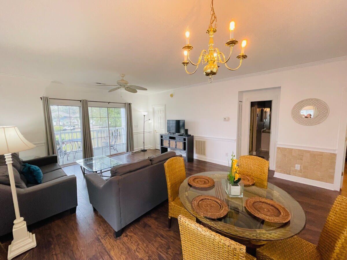 A living room with a sofa, a glass coffee table, and a dining table with chairs.