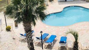 Una piscina con lettini e palme.