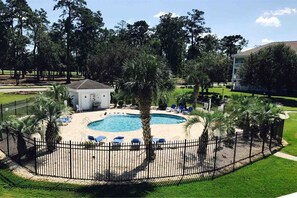 Un espace piscine doté d’une terrasse entourée d’une clôture, de chaises longues et d’un petit bâtiment.