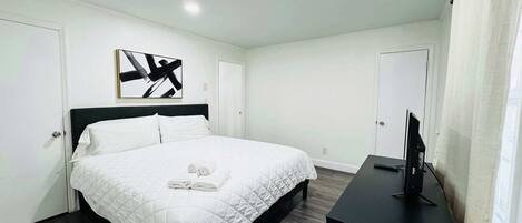 Una habitación de hotel con una cama, un televisor y un cuadro en la pared.