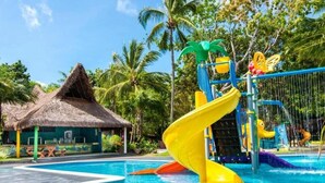 Una piscina con un tobogán amarillo, una cabaña con techo de paja y palmeras.