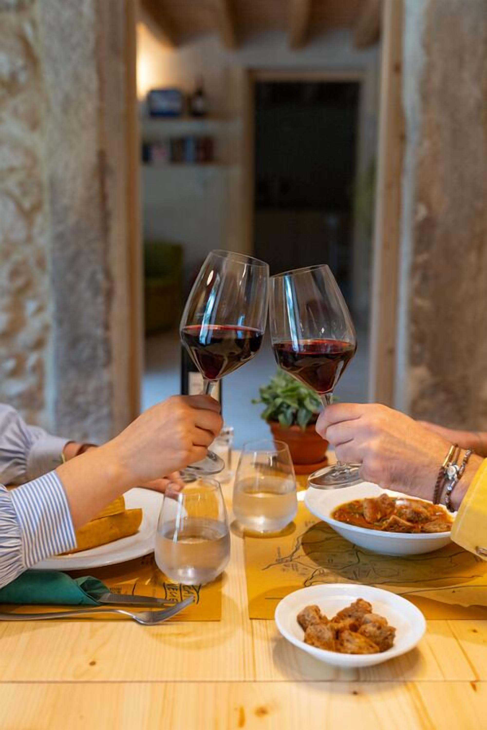 A dining table with two wine glasses, a plate of food, and a bowl of meatballs.