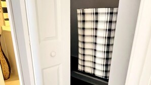A narrow hallway with a white door, a black shelf with a plaid curtain, and a tiled floor. - AW3 Stay close to the beach (Myrtle Beach)