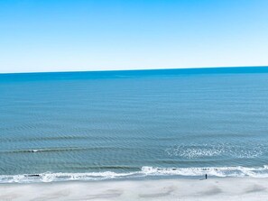 Une plage avec une eau d’un bleu limpide et un rivage sablonneux.