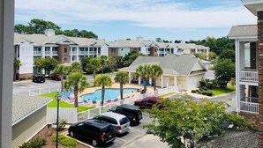 Vista de una zona residencial con piscina, varios edificios de apartamentos y automóviles estacionados.