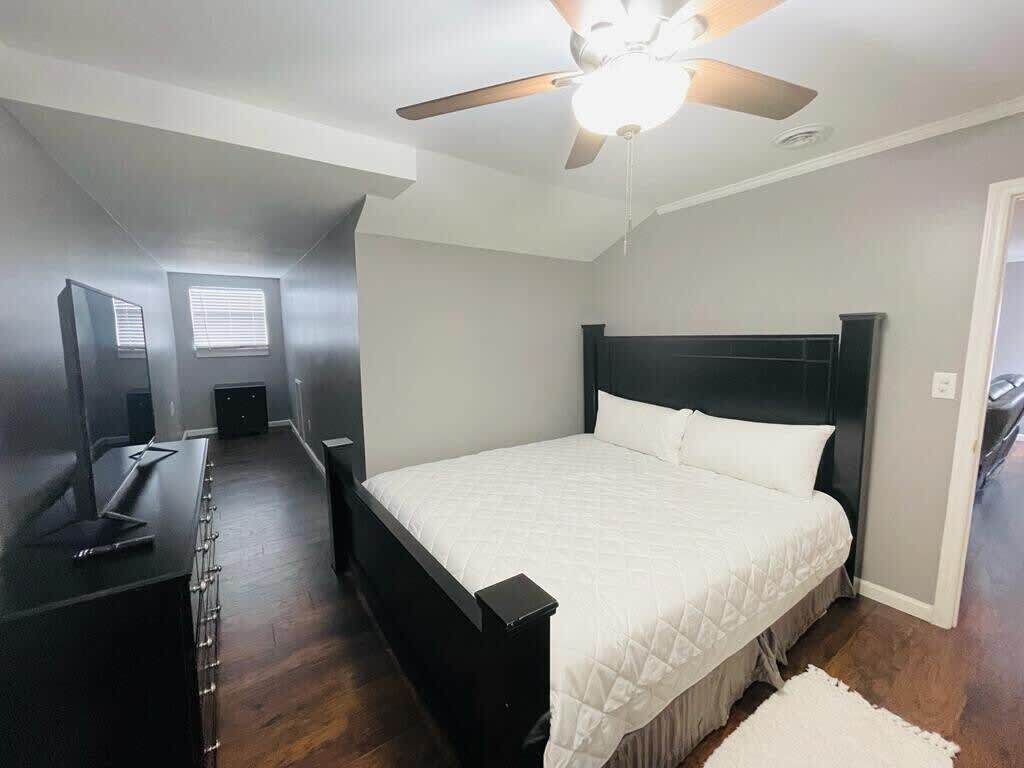 Une chambre à coucher avec un lit, un bureau, un ventilateur de plafond et une fenêtre.
