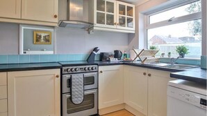 A kitchen with white cabinets, a stove, a dishwasher, and a window with a view of houses. - haven Valley  near the theme park  (Old Windsor)