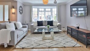 A modern living room with a sofa, coffee table, and a TV mounted on the wall. - haven Valley  near the theme park  (Old Windsor)