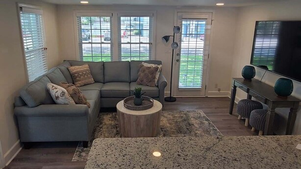 A living room with a sectional sofa, a round coffee table, a TV on a stand, and a large window with blinds. - Walking distance to the the beach beautiful Villa (Myrtle Beach)