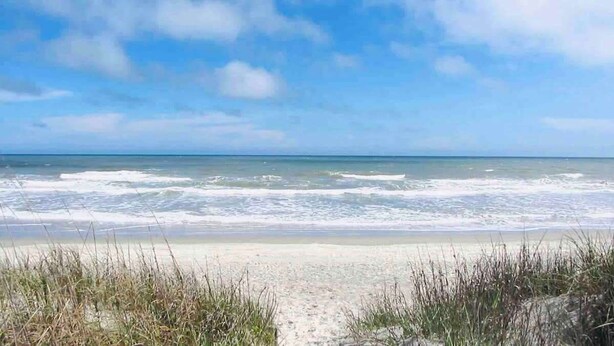 A beach with a sandy path leading to the water, surrounded by grass. - Ocean Dunes Villas #17, short walk to the beach (Myrtle Beach)