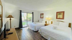 A hotel room with two beds, a TV, and a large window. - Ocean Dunes Villas #17, short walk to the beach (Myrtle Beach)