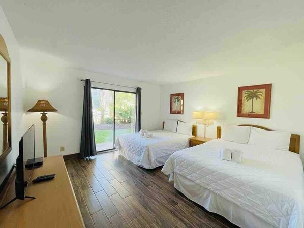 A hotel room with two beds, a TV, and a large window.