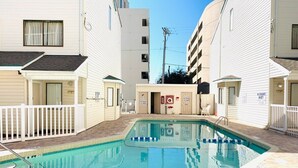 A swimming pool area with a 3 FT depth marker, surrounded by white buildings with balconies and a brick walkway. - Ocean Dunes Villas #17, short walk to the beach (Myrtle Beach)