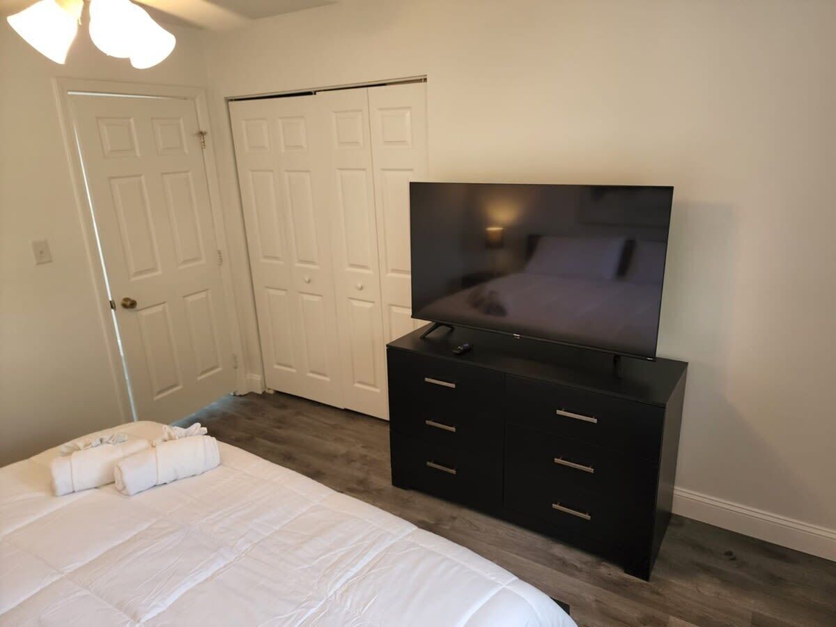 Een slaapkamer met een bed, een dressoir, een televisie en een kast.