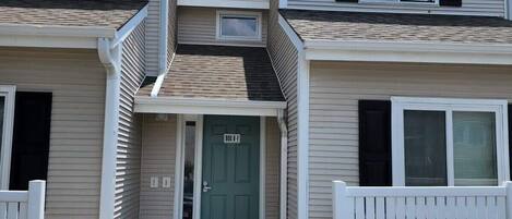 A two-story apartment building with a front entrance, a small porch, and a mailbox.