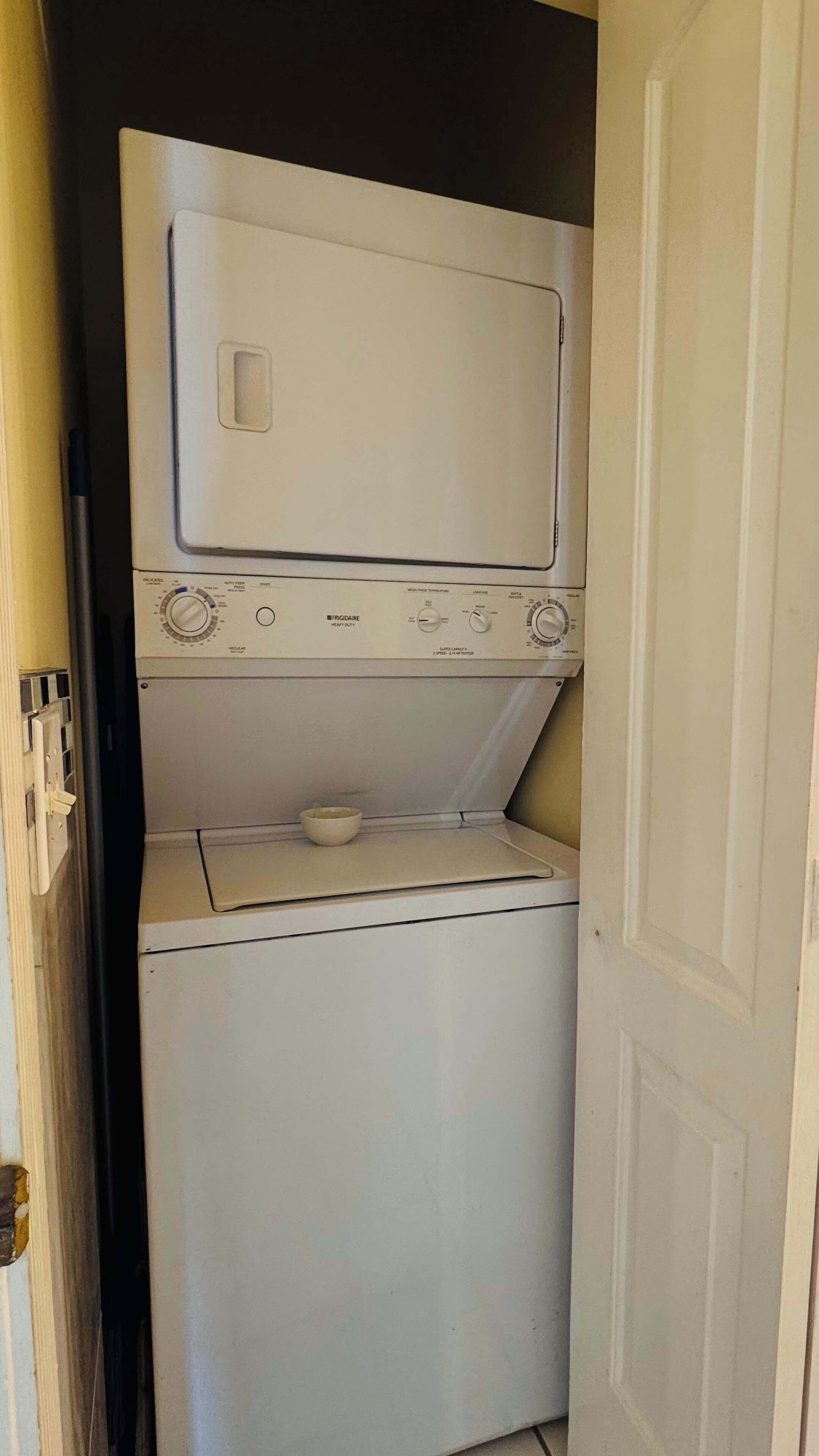 A compact, two-door laundry room with a front-loading washer and dryer.