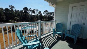 En overdækket veranda med pool, to Adirondack-stole og en dør.