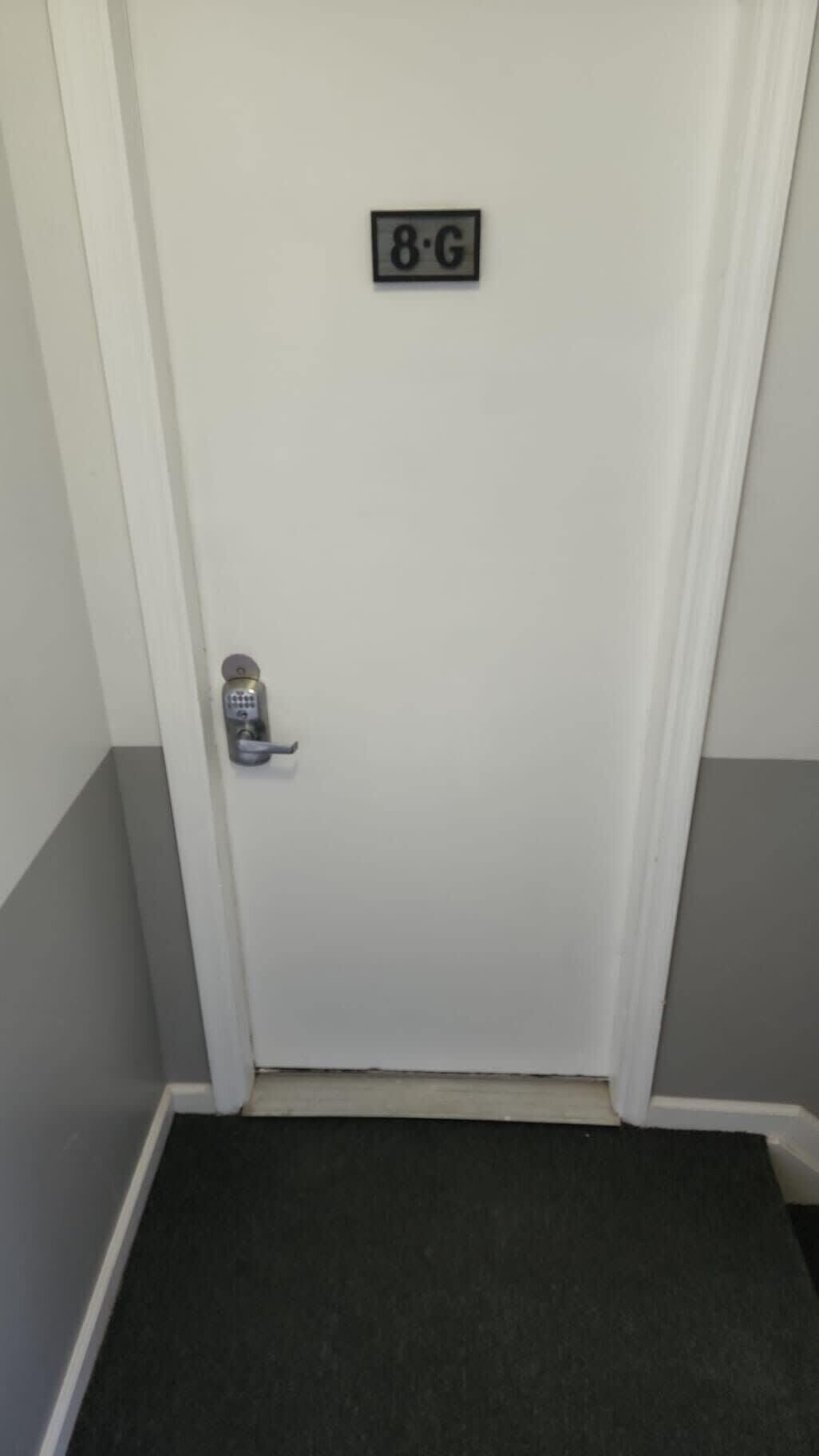 Une porte blanche dotée d’un clavier numérique et d’une plaque signalétique au-dessus.