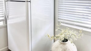 Un refrigerador blanco en una habitación con paredes blancas y suelo de madera.