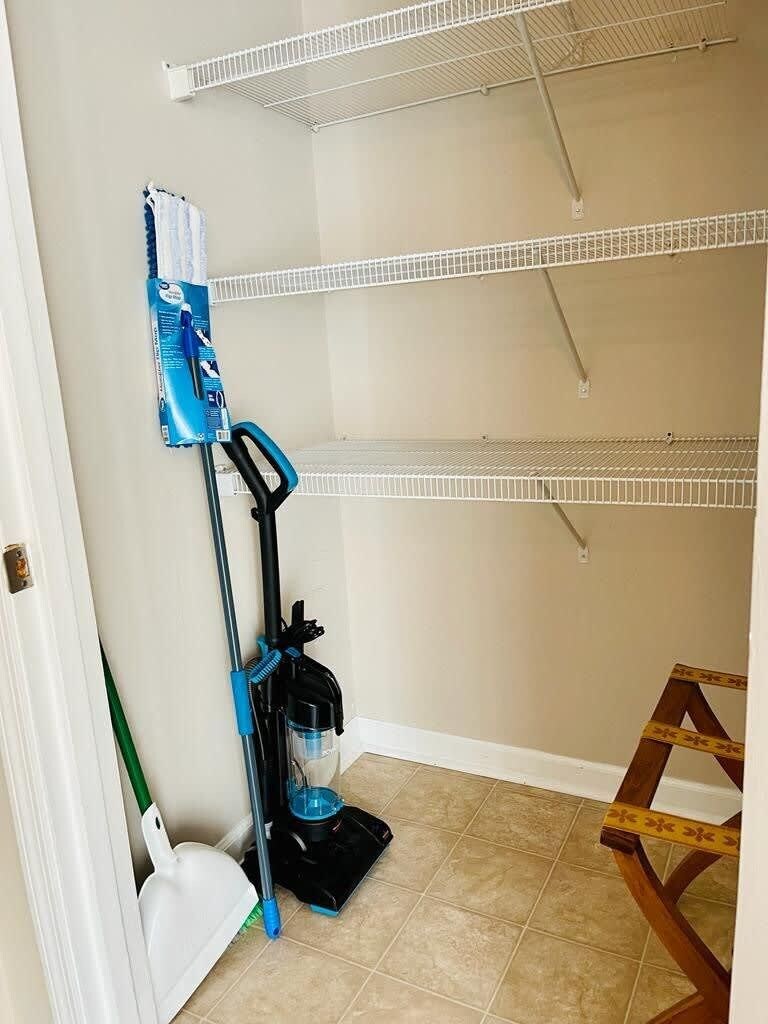 A room with a mop, a broom, and a ladder against the wall.