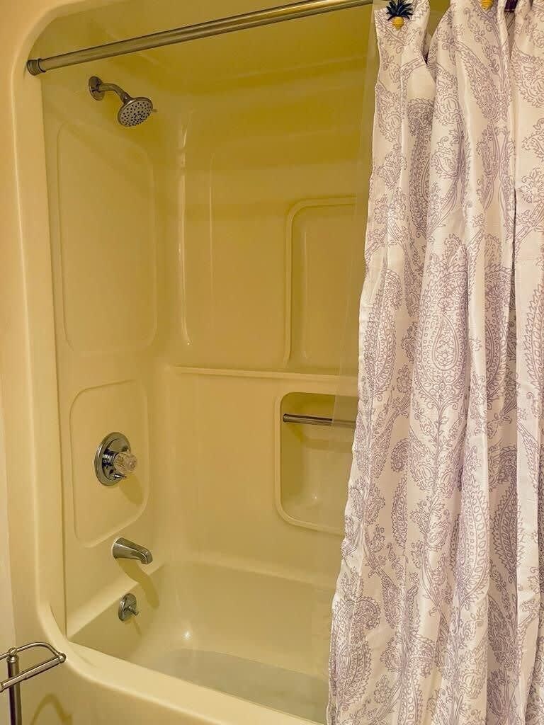 A bathtub with a showerhead, a handheld shower, and a handheld faucet.