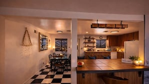 Una cocina moderna con armarios de madera, piso a cuadros blanco y negro y un comedor con mesa y sillas.