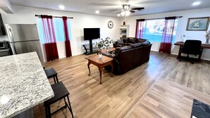 Ein modernes Wohnzimmer mit einer braunen Ledersofa, einem Holzesstisch und einem Deckenventilator.