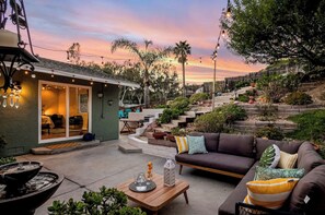 A cozy outdoor patio with a sofa, a dining table, and a small kitchen area. - Tiered garden beach home-Gameroom, Garden, Deck, mts to Beaches,Lagoon, Legoland (Carlsbad)