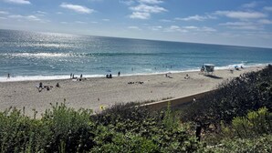 Une plage avec des gens, une tour de surveillance des sauveteurs et un ciel dégagé.